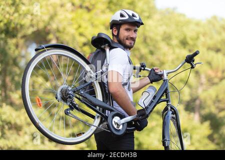 ciclista maschile che porta la sua bicicletta Foto Stock