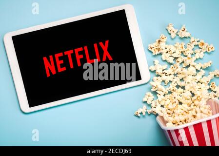 Logo Netflix sullo schermo di un tablet digitale bianco con popcorn su sfondo blu Foto Stock