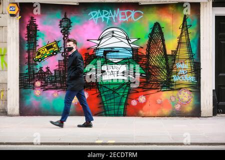 Londra, Regno Unito. 12 Feb 2021.UN uomo con una maschera facciale cammina attraverso Paramedic e Covid-19 Street art su Oxford Street. Credito: Waldemar Sikora Foto Stock