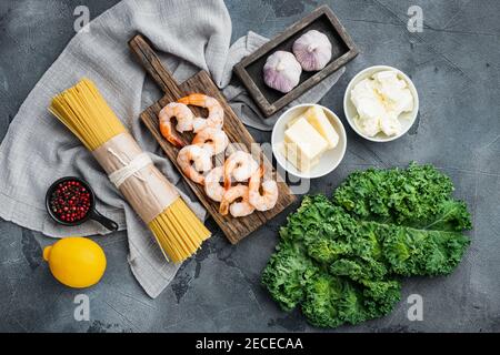 Ingredienti per pasta con frutti di mare. Gamberetti, spaghetti, parmigiano, ricotta, su fondo grigio, vista dall'alto in piano Foto Stock