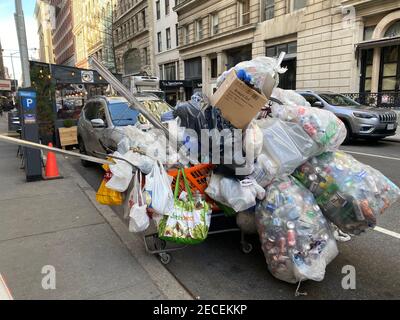 Carrello di spesa sovraccarico con rottami di metallo, alluminio, plastica e bottiglie di vetro raccolti. Via, manhattan. Foto Stock