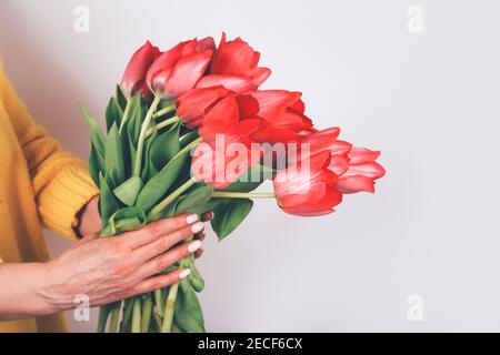 Bel bouquet luminoso di fiori. Miglior regalo per donna l'8 marzo. Mani di donna che tengono mazzo di tulipani Foto Stock