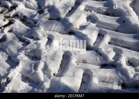 I cingoli degli pneumatici del trattore nella neve in inverno Foto Stock