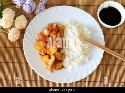 Pollo in salsa dolce e aspre con ananas, paprika e riso. Cucina asiatica Foto Stock