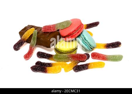 Dolci multicolore isolati su sfondo bianco. Barretta di cioccolato al latte, gelatine acerde e macaroni colorati Foto Stock