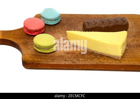 Dolci multicolore isolati su sfondo bianco. Barretta di cioccolato al latte, cheesecake al limone e amaretti colorati Foto Stock