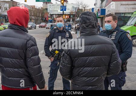 New York, Stati Uniti. 13 Feb 2021. Gli ufficiali del New York City Police Department (NYPD) Pecoraro e Riveiro, dal distretto del 114 indossando maschere protettive, consegnano i volantini ai pedoni come parte di Vision Zero. La Vision Zero di New York City è un'iniziativa a livello di città volta a ridurre i decessi e le lesioni gravi nel traffico attraverso l'ingegneria, l'applicazione e l'istruzione. Credit: SOPA Images Limited/Alamy Live News Foto Stock