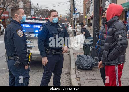 New York, Stati Uniti. 13 Feb 2021. Gli ufficiali del New York City Police Department (NYPD) Pecoraro e Riveiro, dal distretto del 114 indossando maschere protettive, consegnano volantini a conducenti e pedoni come parte di Vision Zero. La Vision Zero di New York City è un'iniziativa a livello di città volta a ridurre i decessi e le lesioni gravi nel traffico attraverso l'ingegneria, l'applicazione e l'istruzione. Credit: SOPA Images Limited/Alamy Live News Foto Stock