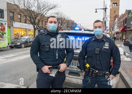 New York, Stati Uniti. 13 Feb 2021. Gli ufficiali del New York City Police Department (NYPD) Pecoraro e Riveiro, dal distretto del 114 indossando maschere protettive, consegnano volantini a conducenti e pedoni come parte di Vision Zero. La Vision Zero di New York City è un'iniziativa a livello di città volta a ridurre i decessi e le lesioni gravi nel traffico attraverso l'ingegneria, l'applicazione e l'istruzione. Credit: SOPA Images Limited/Alamy Live News Foto Stock