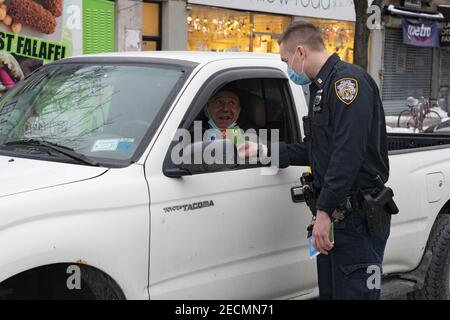 New York, Stati Uniti. 13 Feb 2021. Riveiro, ufficiale del New York City Police Department (NYPD), dal distretto del 114 indossando maschere protettive, offre opuscoli a un conducente come parte di Vision Zero. La Vision Zero di New York City è un'iniziativa a livello di città volta a ridurre i decessi e le lesioni gravi nel traffico attraverso l'ingegneria, l'applicazione e l'istruzione. Credit: SOPA Images Limited/Alamy Live News Foto Stock