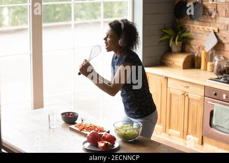 Vista dall'alto donna afroamericana che indossa cuffie che cantano nel whisk Foto Stock