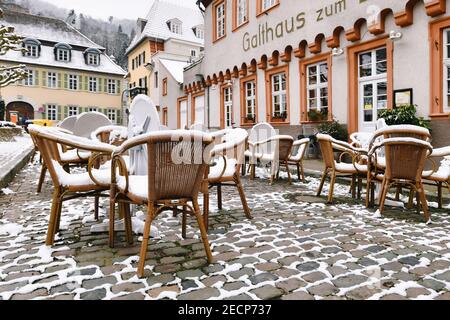 Heidelberg, Germania - Febbraio 2020: Tavoli vuoti con sedie coperte di neve di fronte al ristorante all'aperto nel centro storico della città di Heidelberg Foto Stock