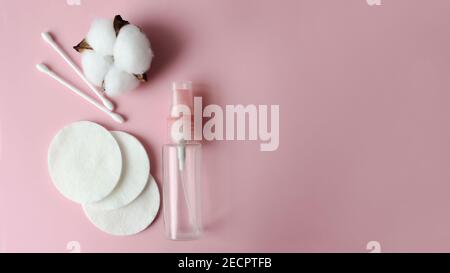 imbottiture in cotone, bottiglia in plastica, bastoncini per le orecchie e cotone su sfondo rosa, vista dall'alto. Bellezza, cura della pelle, dei capelli o del corpo Foto Stock