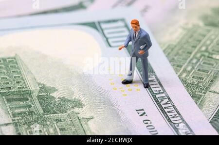 Figurine uomo d'affari su banconota da dollaro. Uomo di affari sta sul concetto di soldi. Economia moderna e crescita finanziaria. Uomo d'affari che parla. Redditizio Foto Stock