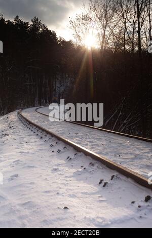 La curva della ferrovia sotto la neve in una bella giornata fredda inverno Foto Stock