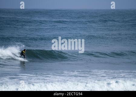 Un surfista corre in modo sportivo lungo un'onda su una spiaggia In Portogallo sull'Oceano Atlantico Foto Stock