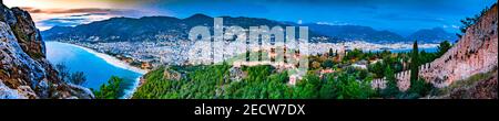 Panorama aereo di Alanya, Turchia con il castello, le montagne, la città e la costa durante l'ora blu di notte Foto Stock