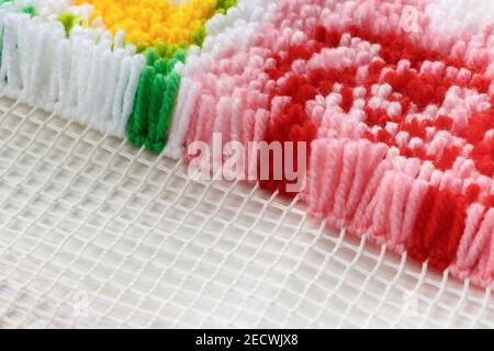Realizzazione di un tappeto con un lungo palo di lana multicolore filettature su una tela speciale Foto Stock