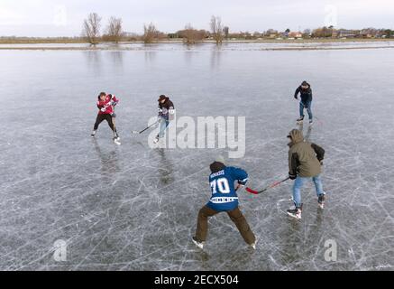 La gente gioca a hockey su ghiaccio su campi ghiacciati allagati vicino Ely a Cambridgeshire, mentre il freddo scatto continua a afferrare gran parte della nazione. Data immagine: Domenica 14 febbraio 2021. I Cambridgeshire Fens sono stati il luogo di nascita del pattinaggio di velocità britannico e richiedono quattro notti di gelo, con una temperatura di -4 o più freddo e poco o nessun scongelamento durante i giorni intermedi, per rendere il ghiaccio abbastanza forte per pattinare. Foto Stock