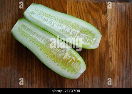 Cetrioli freschi a fette verdi per insalata estiva su un tavolo da cucina di legno marrone. Foto Stock