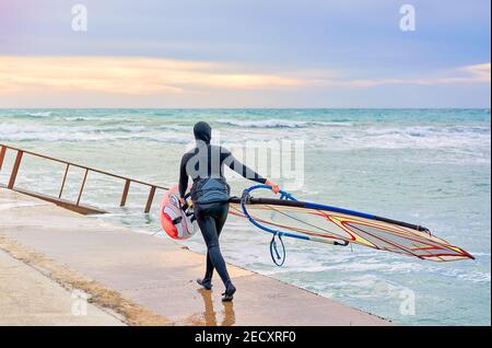 Winter Windsurf, l'uomo in muta windsurf in inverno, in fondo si può vedere il bar ghiaccio Foto Stock