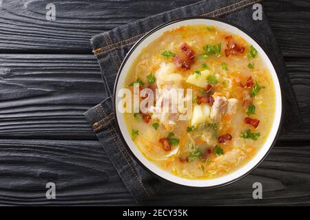 Deliziosa zuppa di crauti polacchi con verdure, costolette e pancetta da vicino in un piatto sul tavolo. Vista dall'alto orizzontale Foto Stock
