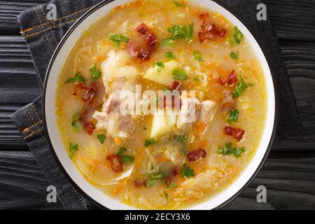 Polish zuppa di crauti Kapusniak con costolette e pancetta primo piano in un piatto sul tavolo. Vista orizzontale dall'alto Foto Stock