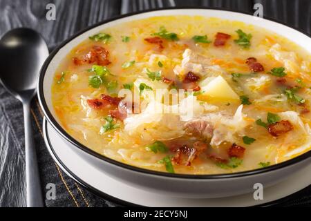 Deliziosa zuppa di crauti polacchi con verdure e costolette e pancetta primo piano in un piatto sul tavolo. Orizzontale Foto Stock