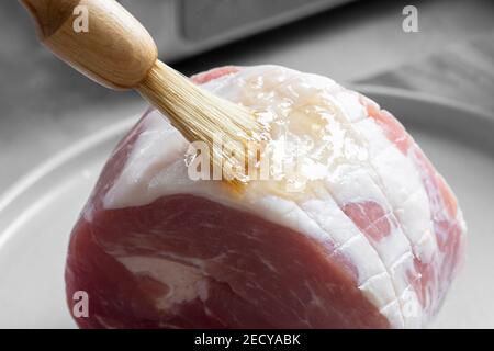 Smalti un prosciutto crudo di gammon con un pennello. Glassa di miele e marmellata Foto Stock