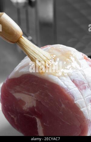 Smalti un prosciutto crudo di gammon con un pennello. Glassa di miele e marmellata Foto Stock