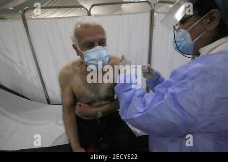 Beirut, Libano. 14 Feb 2021. Un anziano membro del personale del Saint George Hospital riceve una dose di vaccino contro COVID-19 a Beirut, Libano, il 14 febbraio 2021. Il Libano ha lanciato domenica la sua campagna di vaccinazione iniziando con i dipendenti nel settore sanitario dopo aver ricevuto, un giorno prima, 28,500 vaccini da Pfizer-BioNTech, LBCI canale TV locale riferito. Credit: Bilal Jawich/Xinhua/Alamy Live News Foto Stock