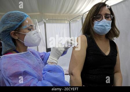 Beirut, Libano. 14 Feb 2021. Un membro del personale del Saint George Hospital riceve una dose di vaccino contro COVID-19 a Beirut, Libano, il 14 febbraio 2021. Il Libano ha lanciato domenica la sua campagna di vaccinazione iniziando con i dipendenti nel settore sanitario dopo aver ricevuto, un giorno prima, 28,500 vaccini da Pfizer-BioNTech, LBCI canale TV locale riferito. Credit: Bilal Jawich/Xinhua/Alamy Live News Foto Stock
