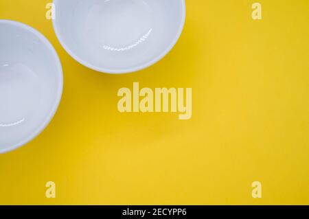 Le piccole ciotole bianche isolate su sfondo giallo Foto Stock