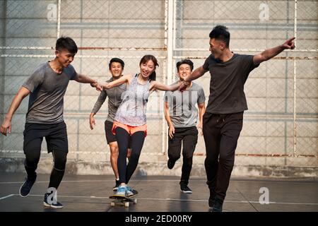 giovani asiatici adulti uomini e donne che si divertono con skateboard all'aperto Foto Stock