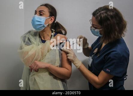 Beirut, Libano. 14 Feb 2021. Un infermiere riceve una dose di vaccino Pfizer/BioNTech coronavirus (COVID-19) presso l'American University Medical Center dopo che il Libano ha ricevuto ieri, sabato, la prima partita di vaccino. Credit: Marwan Naamani/dpa/Alamy Live News Foto Stock