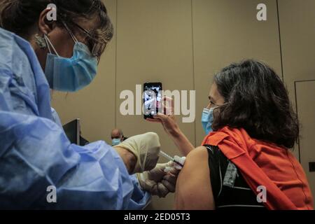 Beirut, Libano. 14 Feb 2021. Una donna prende un selfie come riceve una dose di Pfizer / BioNTech coronavirus (COVID-19) vaccino presso l'American University Medical Center dopo che il Libano ha ricevuto ieri, Sabato, la prima partita di vaccino. Credit: Marwan Naamani/dpa/Alamy Live News Foto Stock