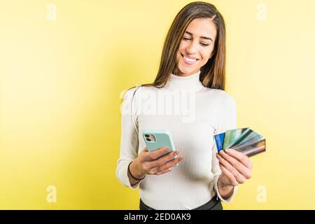 Splendida giovane donna shopping online con smartphone e molti crediti schede Foto Stock