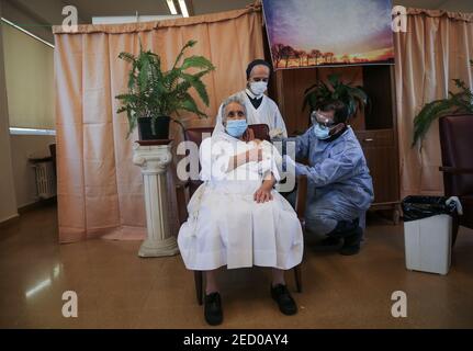 Broumana, Libano. 14 Feb 2021. Una suora riceve una dose di vaccino Pfizer/BioNTech coronavirus (COVID-19) in una casa anziana nel villaggio di Broumana ad est di Beirut. Il Libano inizia la campagna di vaccinazione dopo aver ricevuto ieri, sabato, la prima partita di vaccino. Credit: Marwan Naamani/dpa/Alamy Live News Foto Stock