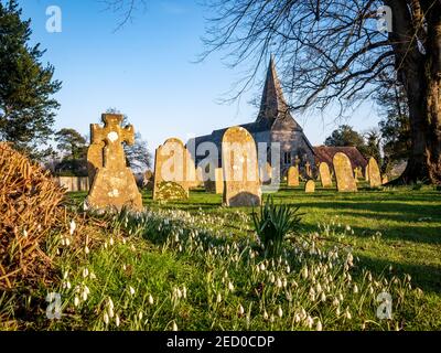 La neve cade nel cortile della chiesa inglese al sole che tramonta Foto Stock