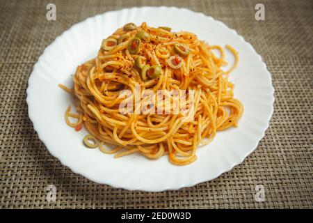 Gustosa e appetitosa pasta italiana di spaghetti con salsa di pomodoro, olive e basilico su piatto. Vista dall'alto, orizzontale Foto Stock