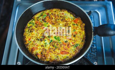 Mescolare l'Omelet Veggie fritto con le verdure in una padella sul fornello a gas. Indiano Nepalese stile Masala Omelet Foto Stock