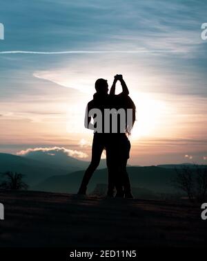 Danza giovane coppia in silhouette durante l'alba in Cappadocia, cielo colorato sullo sfondo Foto Stock