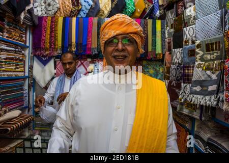 Uomo tradizionale vestito in un negozio di stoffe, città vecchia di Jeddah, Arabia Saudita Foto Stock
