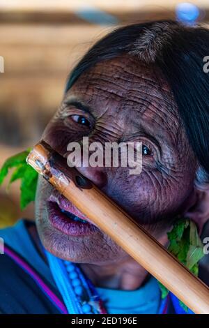 Donna di mento con tatuaggio spiderweb che soffia un flauto con il naso, Kanpelet, Chin stato, Myanmar Foto Stock