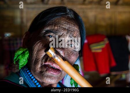 Donna di mento con tatuaggio spiderweb che soffia un flauto con il naso, Kanpelet, Chin stato, Myanmar Foto Stock