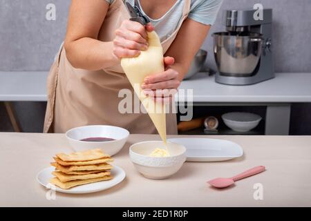 Sacchetto di pasticceria con crema nelle mani di un pasticciere. Processo di preparazione dei dessert. Foto Stock