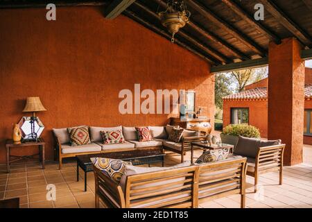 Comodi divani e tavolo posti sulla terrazza sotto il tetto di legno di cottage in estate Foto Stock