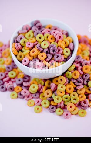 Vista dall'alto di una pila di colorati anelli di cereali nel recipiente preparato per la colazione posto su tavolo viola in studio Foto Stock