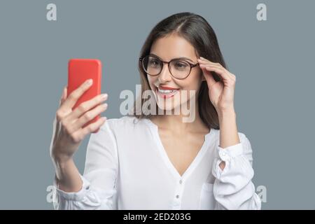 Donna con smartphone in occhiali estensibile per la correzione delle mani Foto Stock