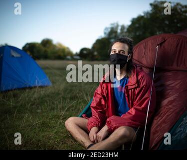 Un attivista maschile di Extinction Rebellion siede fuori dalla sua tenda in un campeggio a Brockwell Park, Londra, 31 agosto 2020 Foto Stock